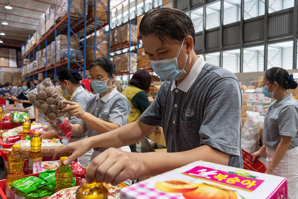 志工在偌大的仓库，发挥蚂蚁雄兵的团体力量，为琳琅满目的年货分类和打包。（摄/ 曾美珍）